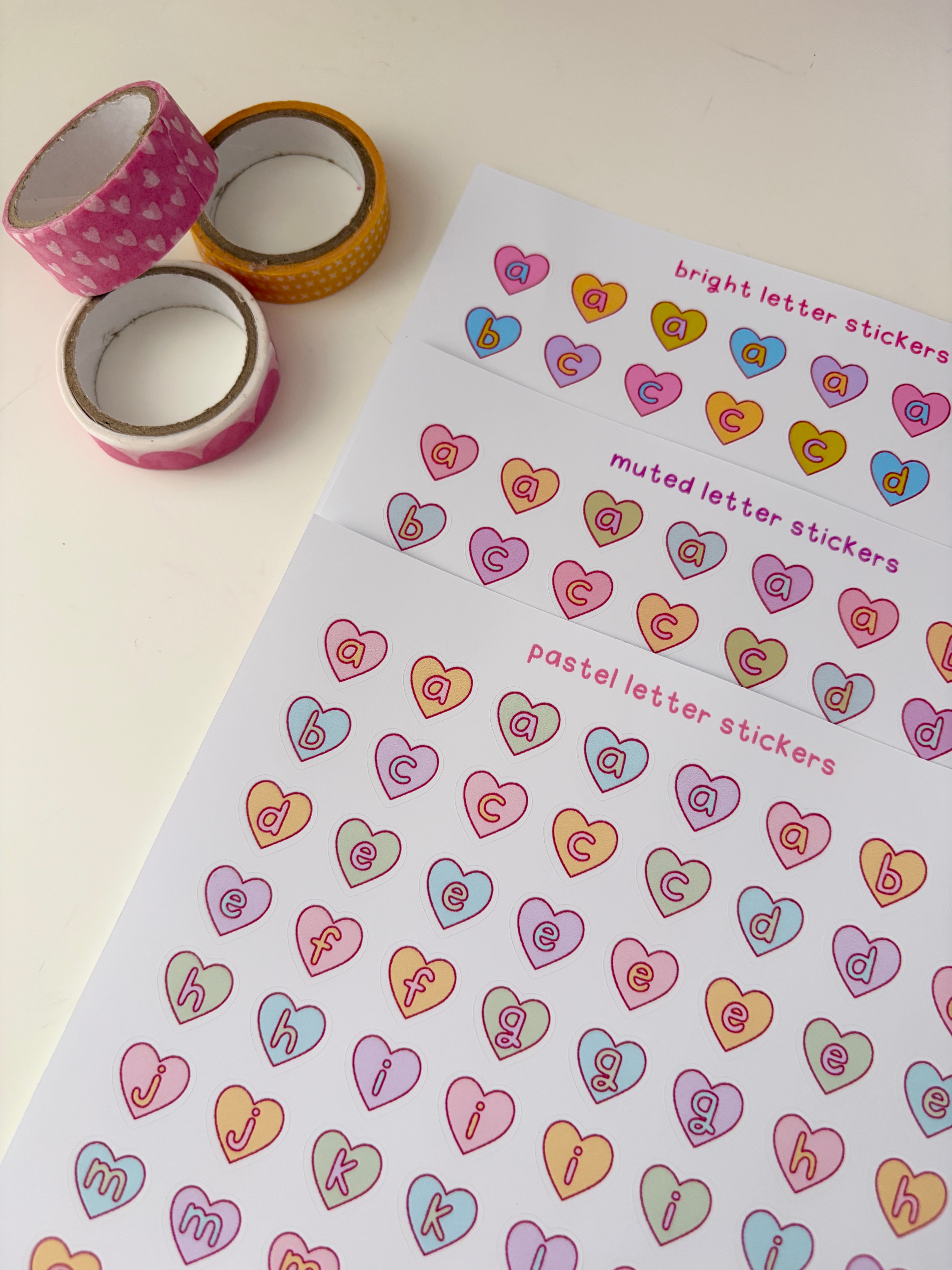 Sheet of letter stickers with colorful letter designs on a white background, accompanied by rolls of decorative tape.