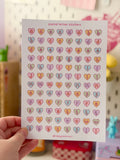 Sheet of pastel letter stickers held by a hand with a blurred background