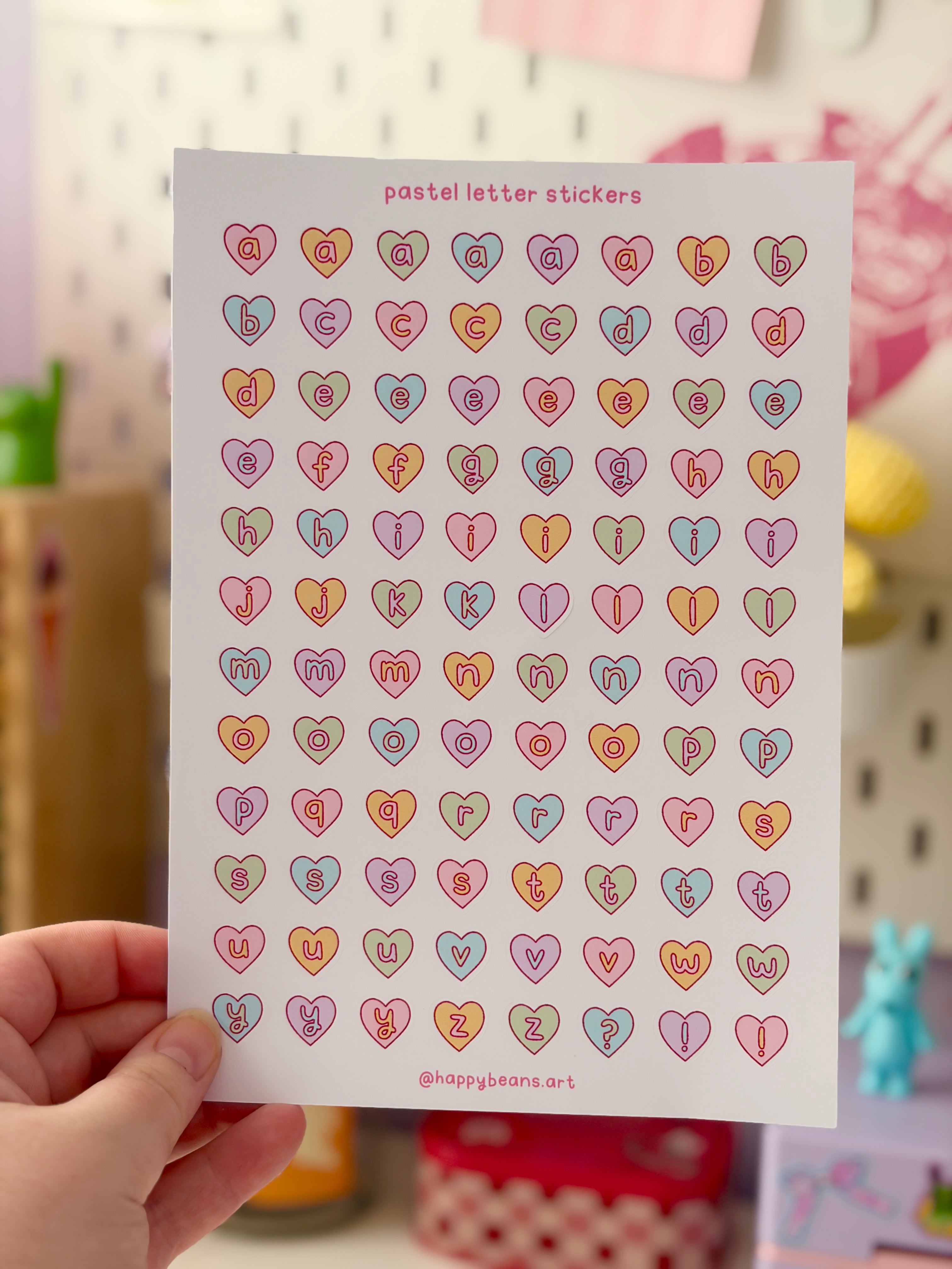 Sheet of pastel letter stickers held by a hand with a blurred background